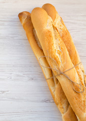 Fresh french baguettes on white wooden surface, top view. Overhead.