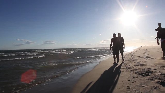 Vacanciers marchant sur la plage le long de la mer M&eacute;dit&eacute;rrann&eacute;e au coucher du soleil
