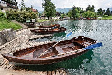 Beautiful Lake Bled in the Julian Alps and two old wooden boats. Mountains, clear aquamarine water, tourist boat, lake and dramatic blue sky.