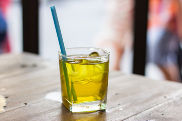 Chrysanthemum iced tea with straw on a wooden table.