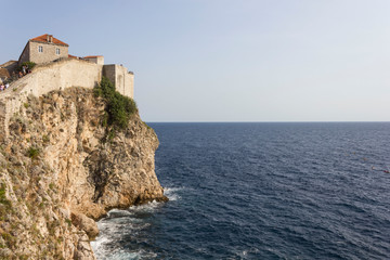 Fototapeta na wymiar DUBROVNIK, CROATIA - AUGUST 22 2017: Dubrovnik defensive stone walls overlooking the cliff and sea horizon