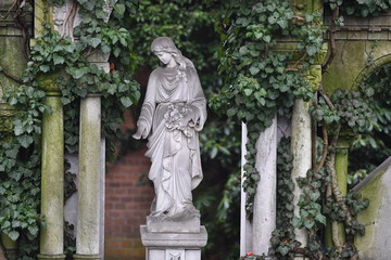 A weathered sandstone sculpture of Maria, the mother of Jesus Christ.