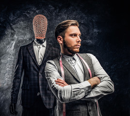 A confident young fashion designer with his arms crossed posing next to a mannequin in exclusive...
