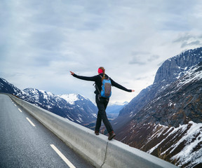 Brave Woman hiker walking to the cliff edge on mountain road, keeping balance.