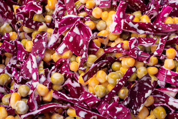 salad of fresh red cabbage with corn and green peas in a creamy sauce or mayonnaise. background texture