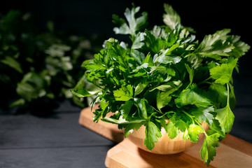 Fresh parsley leaves in bowl on rustic wooden table