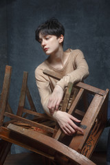 A young girl with short black hair poses on the composition of the chairs.