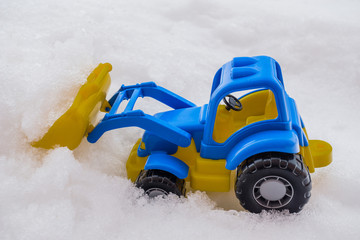 toy tractor with front loader in the snow. concept of utilities and snow removal. road services.