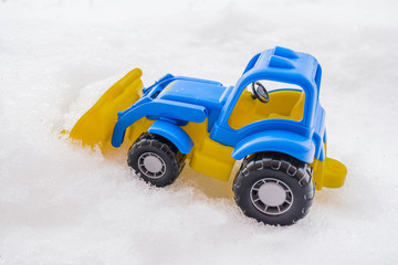 toy tractor with front loader in the snow. concept of utilities and snow removal. road services.