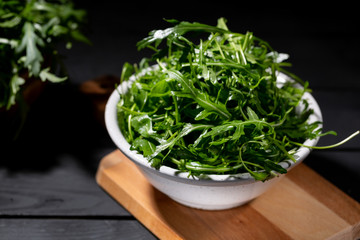 Fresh rocket salad in bowl on the wodden background