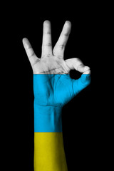 Hand making Ok sign, Canary islands flag painted as symbol of best quality, positivity and success - isolated on black background