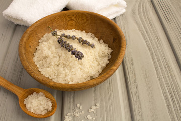 Fototapeta na wymiar Sea bath salt,dried lavender and white towels on the grey wooden background