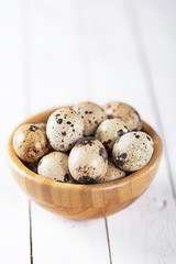 quail eggs in wooden plate over white background