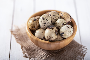 Obraz premium quail eggs in wooden plate over white background