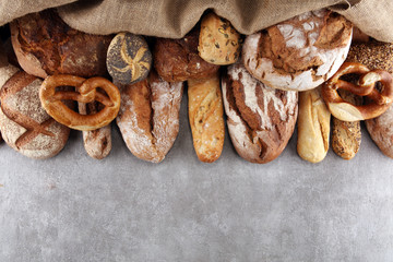 Assortment of baked bread and bread rolls on stone table background