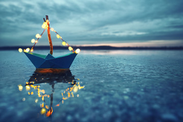 magisches Papierboot mit Lichterkette am Strand