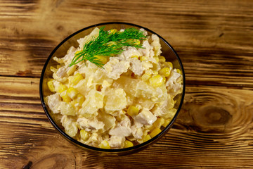 Festive salad with chicken breast, sweet corn, canned pineapple, cheese and mayonnaise on wooden table