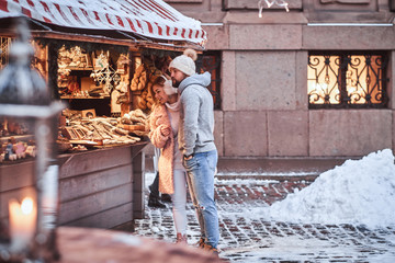 A happy young couple choosing the gift in a souvenir shop outdoors on a winter fair at a Christmas...