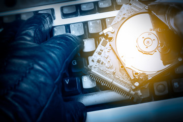 Cybercriminal's hand on a keyboard. Hacked computer hard drive. Cybercrime concept