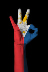 Hand making Ok sign, philippines flag painted as symbol of best quality, positivity and success - isolated on black background