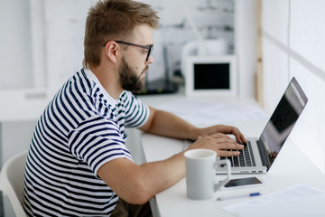 business man sitting at desk in office and looking at open laptop workstation.