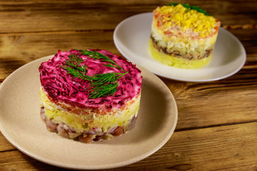 Traditional russian layered salads "Mimosa" and "Herring under a fur coat" (shuba) on wooden table