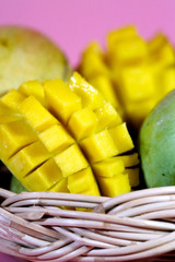 Ripe peeled and unpeeled mango on pastel pink and space for write wording, popular sweet tropical fruit, important export product, high calories and sugar level caused diabetes and other illness
