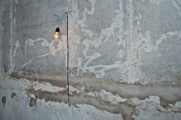 Burning light bulb on the wall of the building. Lighting part of the territory at the construction site.