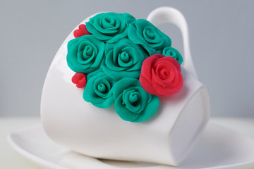 Mug, decorated with flowers made of polymer clay. Crafts from polymer clay. Mug decorated with stucco made of polymer clay