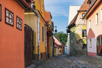 Fototapeta na wymiar Cobbled street with colorful facade of medieval houses in the historic center of Sighisoara, Romania