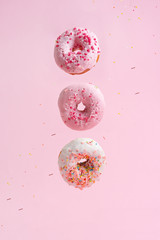 Sprinkle pink donuts. Frosted sprinkle donut on a pink background. Three tasty and sweet donuts