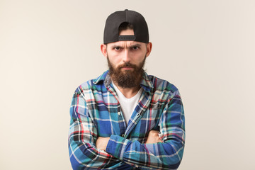 Hipster, lifestyle and people concept - Angry bearded man in a cap posing over the white background