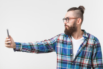 Hipster, people concept - Young hipster with beard in glasses taking selfie