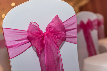 Wedding chairs decorated during the ceremony with a bow