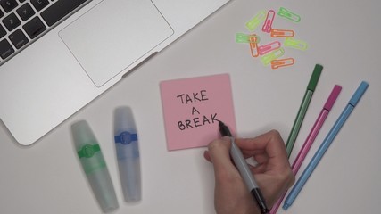 TAKE A BREAK. Woman writing on notepad.