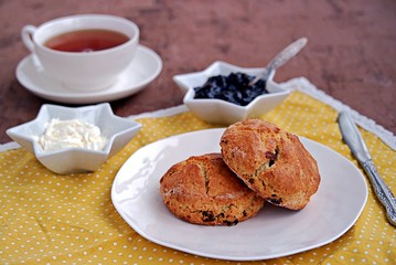 Fototapeta na wymiar Traditional English scones with dried cranberries on a white plate. Served with jam and whipped cream.