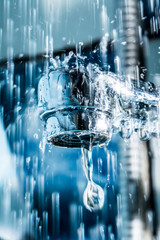 Water flows from a modern chromed water tap faucet macro close-up.