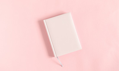 Pink notebook on pink desk. Business minimal concept for women. Flat lay, top view, copy space 