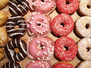 Delicious colourful donuts covered with icing and chocolate on a shop window (in a supermarket). 