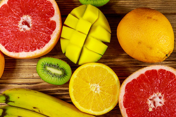 Assortment of tropical fruits on wooden table. Still life with bananas, mango, oranges, grapefruit and kiwi fruits