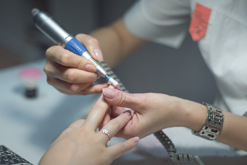 Manicurist master is removing an old nail varnish by hardware manicure. Nail care concept.