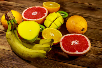 Assortment of tropical fruits on wooden table. Still life with bananas, mango, oranges, grapefruit and kiwi fruits