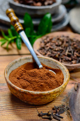 Bowls with dried clove buds and cloves powder, used for cooking and traditional medicine, close up, spices collection