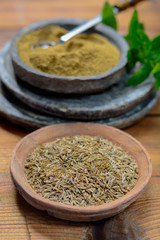 Old clay bowls wirh cumin seeds and cumin powder close up, spices collection
