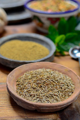 Old clay bowls wirh cumin seeds and cumin powder close up, spices collection
