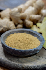 Fresh raw ginger root and bowl with ginger powder close up