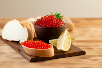 red caviar in a ceramic dish on a wooden background in a rustic style with space for text