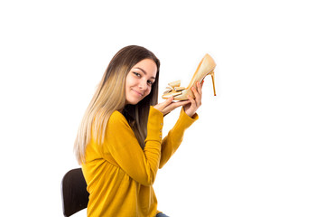 Pretty young woman holding a high heel shoe over white background