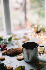 Cup with tea near the window with autumn leaves and cookies