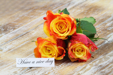 Have a nice day card with three orange roses covered with glitter on wooden surface
